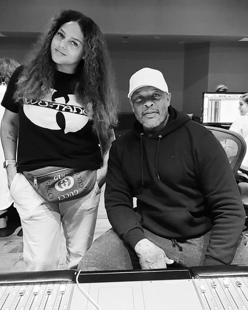 foto em preto e branco que mostra Marsha Ambrosius em pé à esquerda e Dr Dre sentado à direita dentro de um estúdio.